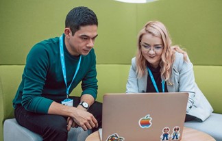 Two colleagues looking at the same laptop