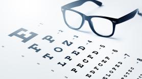 An image of a single pair of black glasses next to an eye test chart.